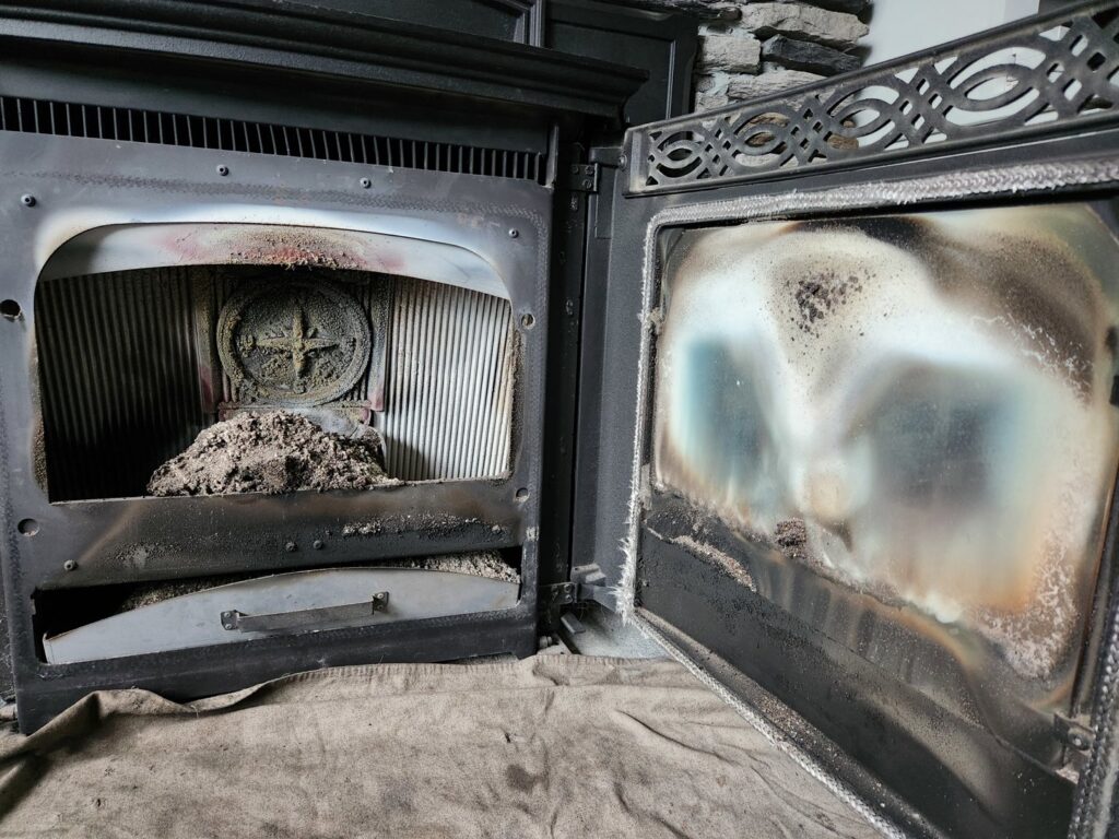 An open pellet stove showing significant ash and creosote buildup before cleaning by Top Dog Hearth Repair & Maintenance, LLC in Worcester, MA