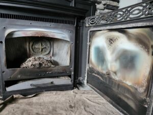 An open pellet stove showing significant ash and creosote buildup before cleaning by Top Dog Hearth Repair & Maintenance, LLC in Worcester, MA