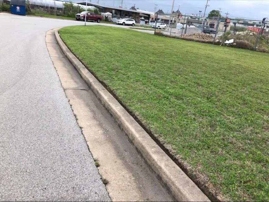 A perfectly edged commercial lawn along a curb, showcasing precise lawn care services by Lande Lawn Care in Broken Arrow, OK.