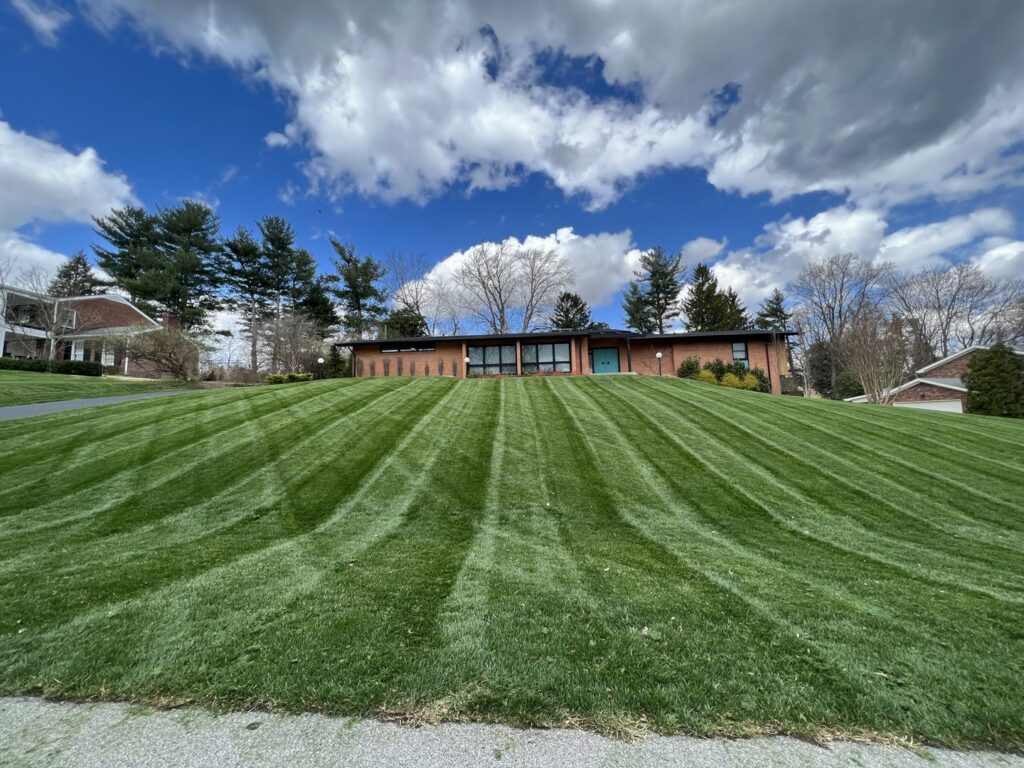 A perfectly mowed lawn with distinct stripes on a residential property by Peek Lawn Care LLC in Windy Hills, KY.