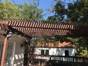 A pergola and deck area with a stained wood fence visible in the background by Texas Tuff Stain and Seal in Fort Worth, TX.