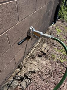 A pest control technician applying perimeter treatment to a building foundation using an injection tool by PestGoat, llc. in Fort Ashby, WV.