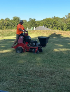 A lawn care professional operating a stand-on aerator machine on a residential lawn for C&R Lawn Care and Property Services in Evansville, IN.