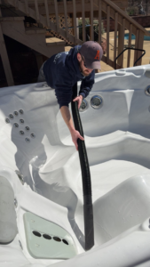 A KS Pool Co. LLC technician cleaning a hot tub with a vacuum in Auburn, AL.