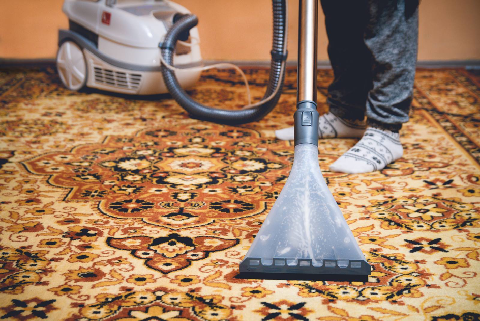 A person using a carpet cleaning machine to clean a patterned oriental rug, demonstrating services by stpaulbestcarpetcleaners.com in Saint Paul, MN.