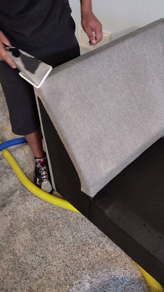 A person cleaning an upholstered sofa with professional equipment by D&D Carpet Cleaning & Janitorial in West Columbia, SC