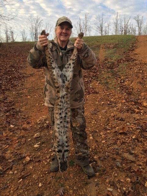 A person in camouflage holding a captured bobcat, showcasing wildlife removal services by ACB Wildlife Control in Memphis, TN.