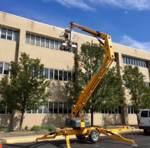 A person in a lift bucket working on the side of a commercial building for Epcon Lane Pest Control in Akron, OH.
