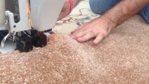 A person operating a carpet binding machine, demonstrating carpet customization and repair services by Carpet Cleaner Staten Island in Staten Island, NY.