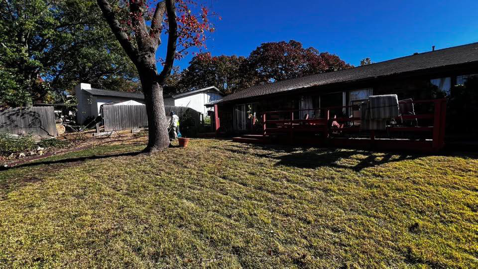 A person raking leaves in a backyard, a service provided by GAMAS Lawn Care Services in Tulsa, OK.