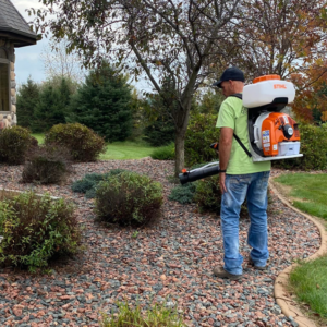 A person using a backpack sprayer to treat bushes for pest control at a residential property by Mosquito Delete-O in Appleton, WI.
