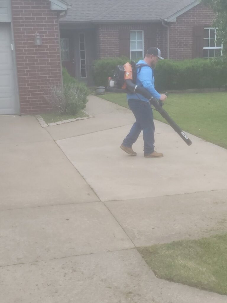 A professional using a backpack leaf blower to clear debris for R & W Lawn care service LLC in Tulsa, OK.