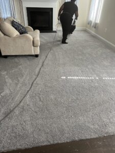 A person vacuuming a newly installed grey carpet in a living room by Danny's Flooring Service LLC in White Plains, MD