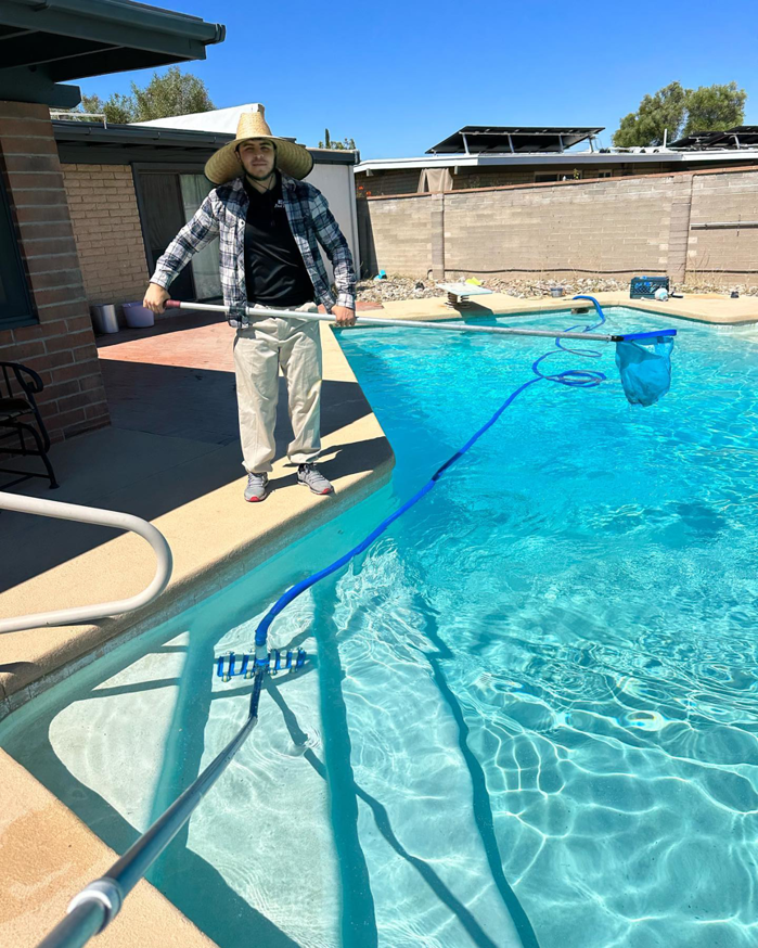 A person actively vacuuming a swimming pool, demonstrating professional cleaning by Az Pool Man in Tucson, AZ.