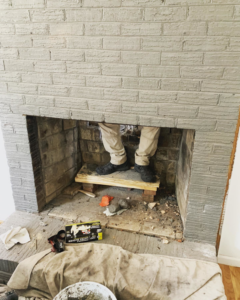 A technician from Emberstone Chimney Solutions working inside a fireplace during a chimney sweep job in Charlotte, NC.