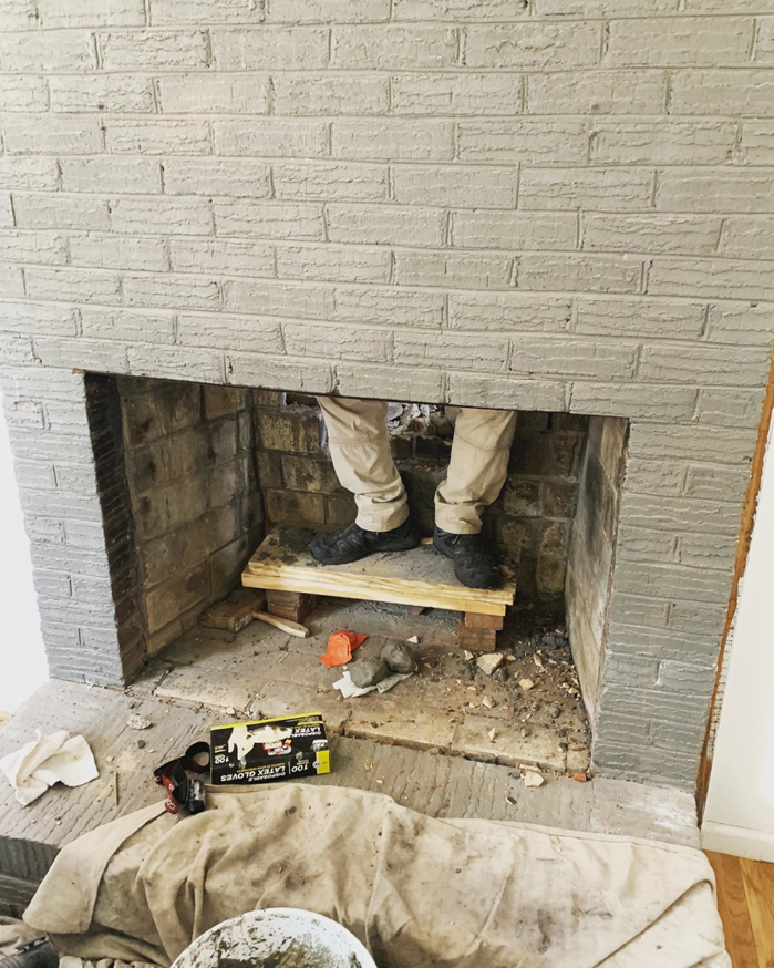 A technician from Emberstone Chimney Solutions working inside a fireplace during a chimney sweep job in Charlotte, NC.