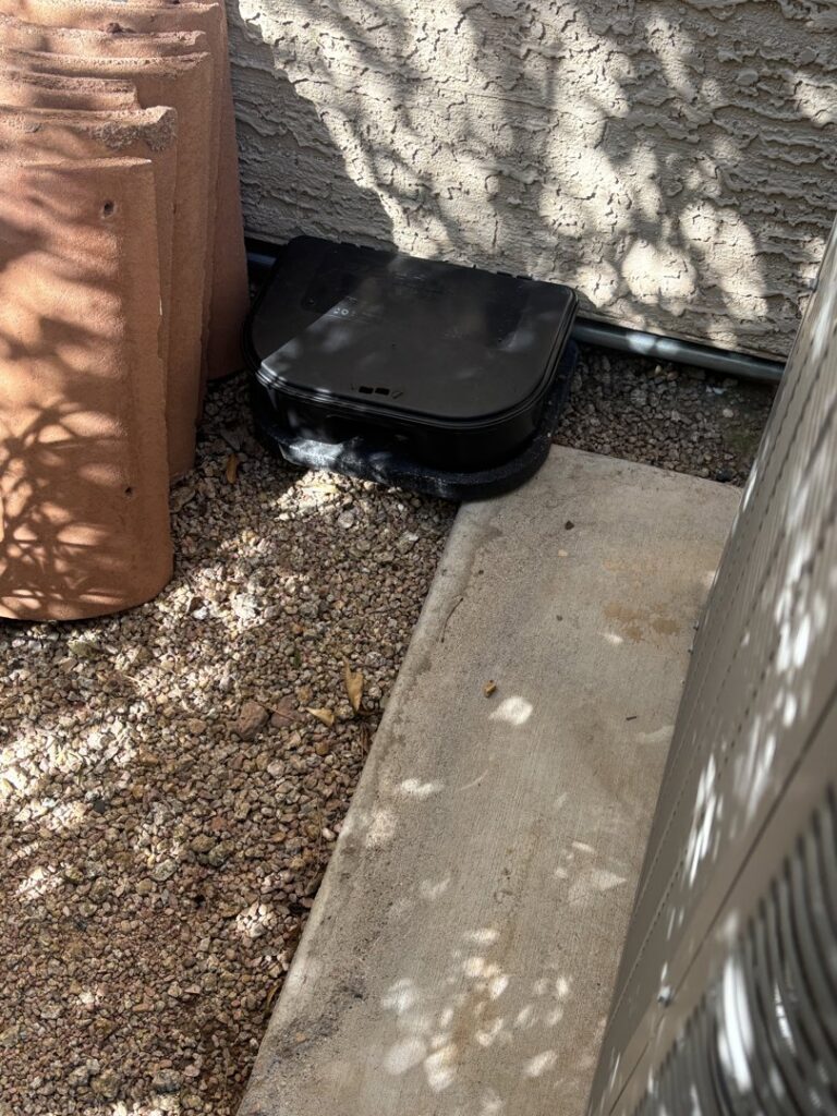 A pest bait station installed next to a house by Sandstorm Pest Control in Chandler, AZ.