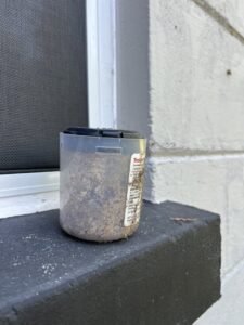 A pest bait station placed on a building ledge for pest management by Crawford Pest Control in Jacksonville, FL.