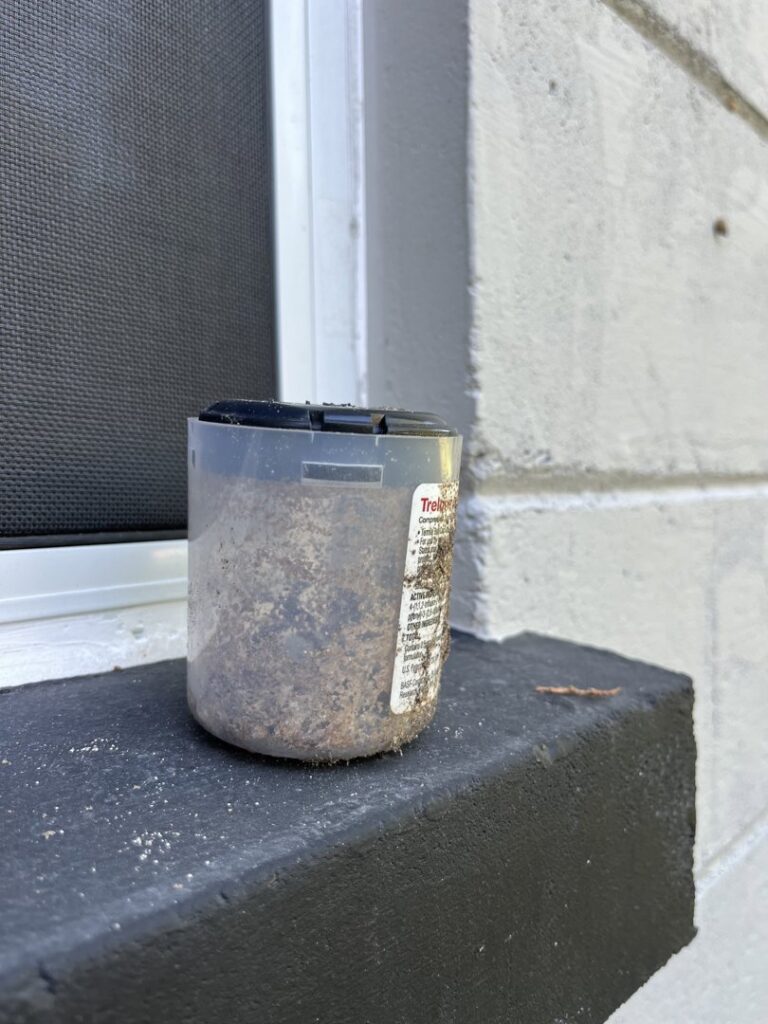 A pest bait station placed on a building ledge for pest management by Crawford Pest Control in Jacksonville, FL.