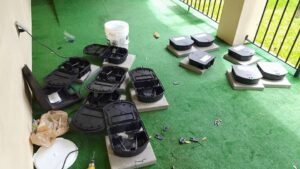 Black pest bait stations laid out on an outdoor carpet, ready for installation by Sellers Pest Control in Summerville, SC.