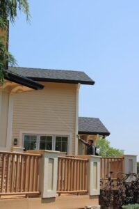 An Upfront Pest technician treating house eaves from a deck for pest control in North Kansas City, MO.