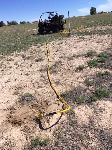 Pest control equipment with a hose inserted into the ground in a field, indicating rodent control by No Moore Pests in Pueblo, CO.
