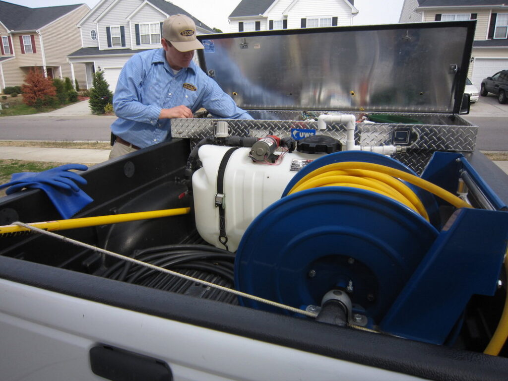 A Stomp Pest Control technician organizing professional pest control equipment in the back of a service truck in Raleigh, NC.
