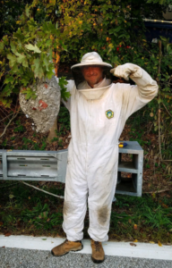 A pest control expert in a protective suit proudly displaying a large wasp nest removed by Akron Pest Control in Akron, OH.