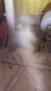Pest control technician performing fogging or spraying treatment in a crawl space for Reliable Pest Management in Springfield, MO.