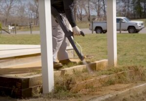 A pest control technician performing a perimeter treatment around a home for Richmond Pest Control in Richmond, KY.