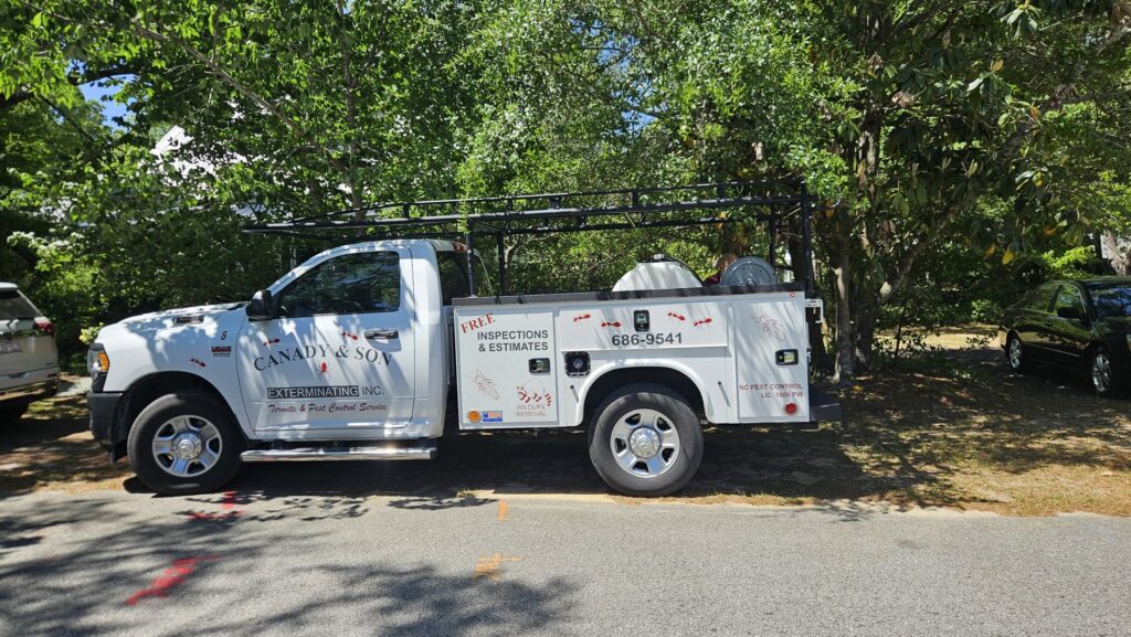 A Canady & Son Exterminating pickup truck with a ladder rack and equipment, parked for a service call in Wilmington, NC.