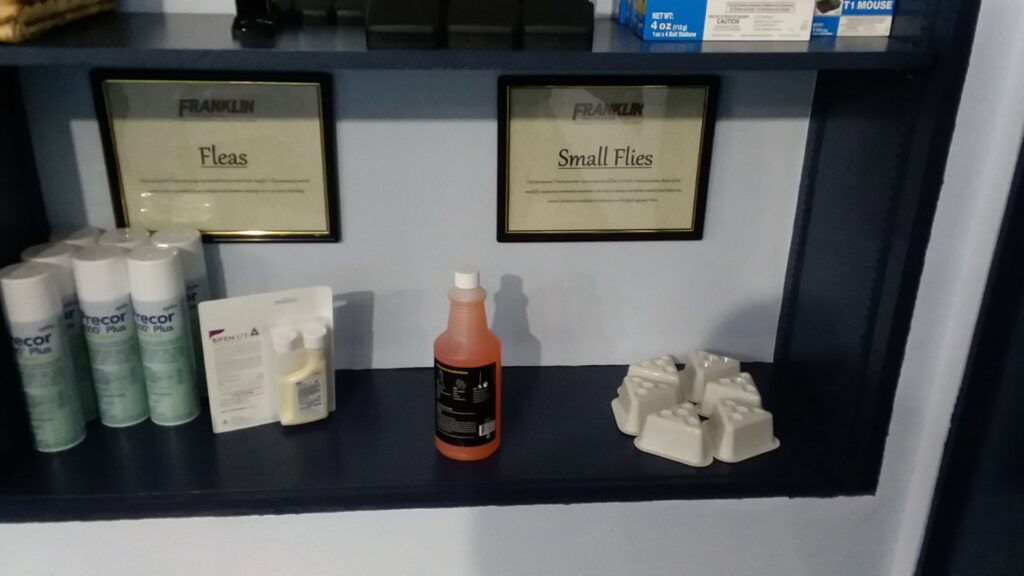 A display shelf featuring various pest control products for fleas and small flies at Franklin Pest Solutions Michigan City in Lafayette, IN.