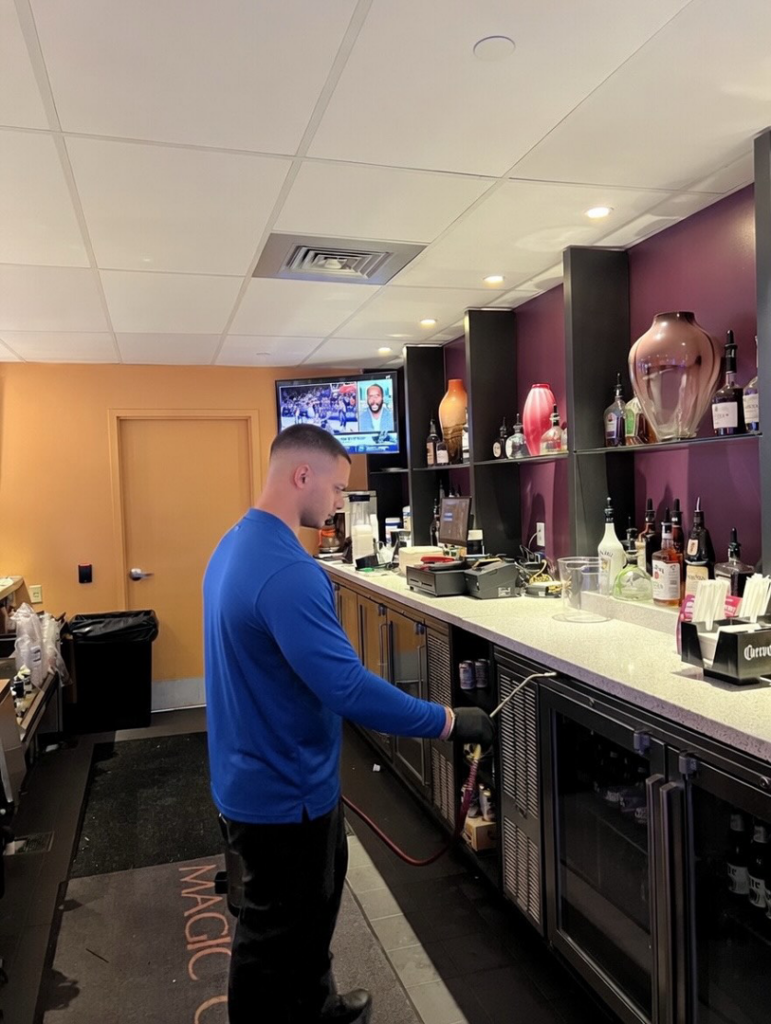 Pest control service being performed by Ideal Pest Control Inc behind a commercial bar counter in Miami, FL.