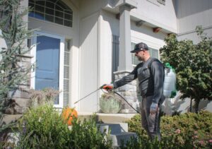 An Upfront Pest technician performing pest control service near a home's front door in North Kansas City, MO.