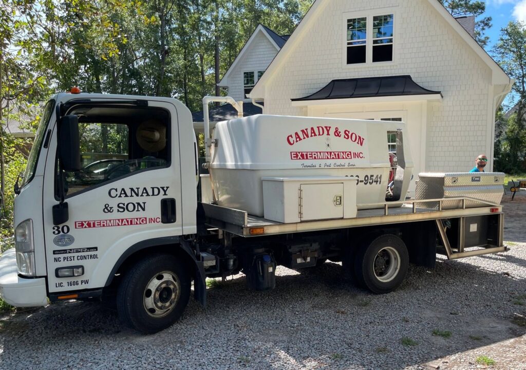 A Canady & Son Exterminating service truck with specialized equipment parked at a client's home in Wilmington, NC.