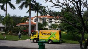 A PowerX Pest Control of South Florida service truck parked in front of a large house in Miami, FL.