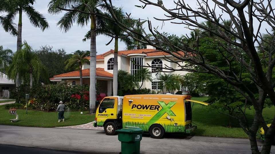 A PowerX Pest Control of South Florida service truck parked in front of a large house in Miami, FL.