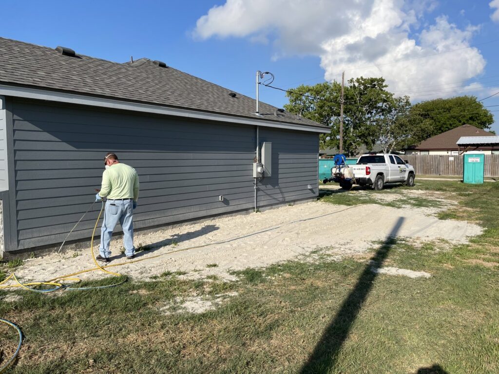 A Solutions Pest Management specialist treating the perimeter of a house for pest control in Corpus Christi, TX.