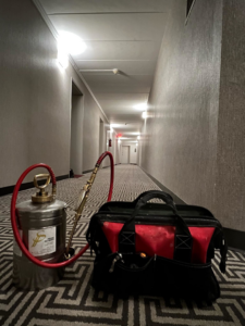 A pest control sprayer and tool bag in a hallway, ready for a job by Prestige Pest Services in Hawthorne, NJ.