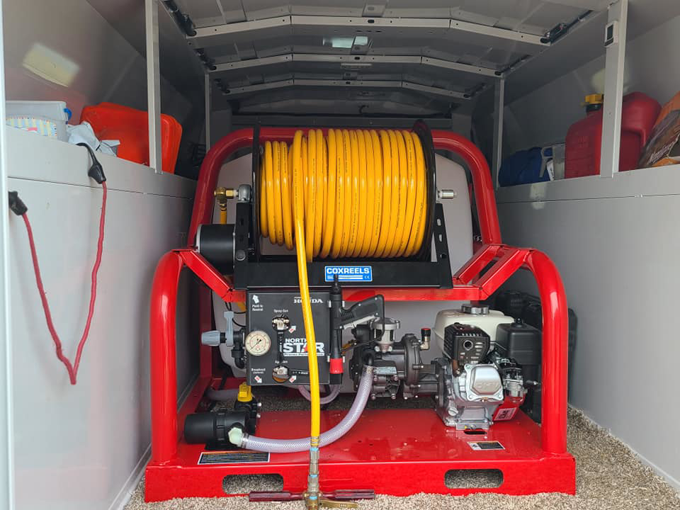 Specialized pest control sprayer equipment with a yellow hose reel inside a Monocacy Pest Control vehicle in New Market, MD.