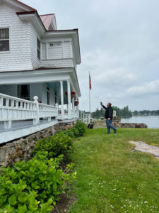 A pest control technician spraying the foundation and landscaping of a house for Professional Pest Control Services in Rush, NY.