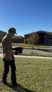 A pest control technician applying granules to a residential lawn for Ozark Pest Control in Fayetteville, AR.
