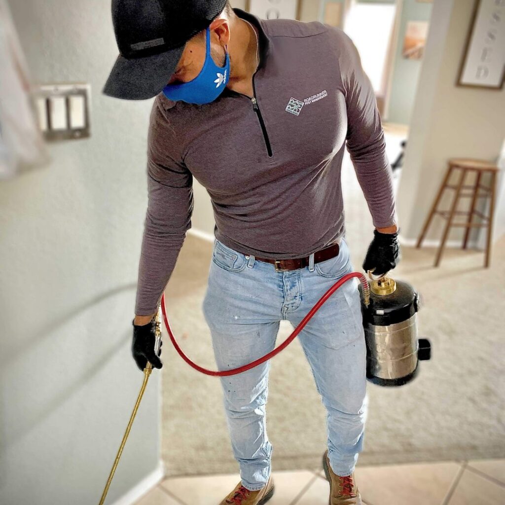 A pest control technician applying treatment with a tank sprayer during a service by RoadRunner Pest Management in Albuquerque, NM.