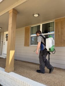 A Rosie's Pest Control technician with a backpack sprayer arriving at a residential home for service in Memphis, TN.
