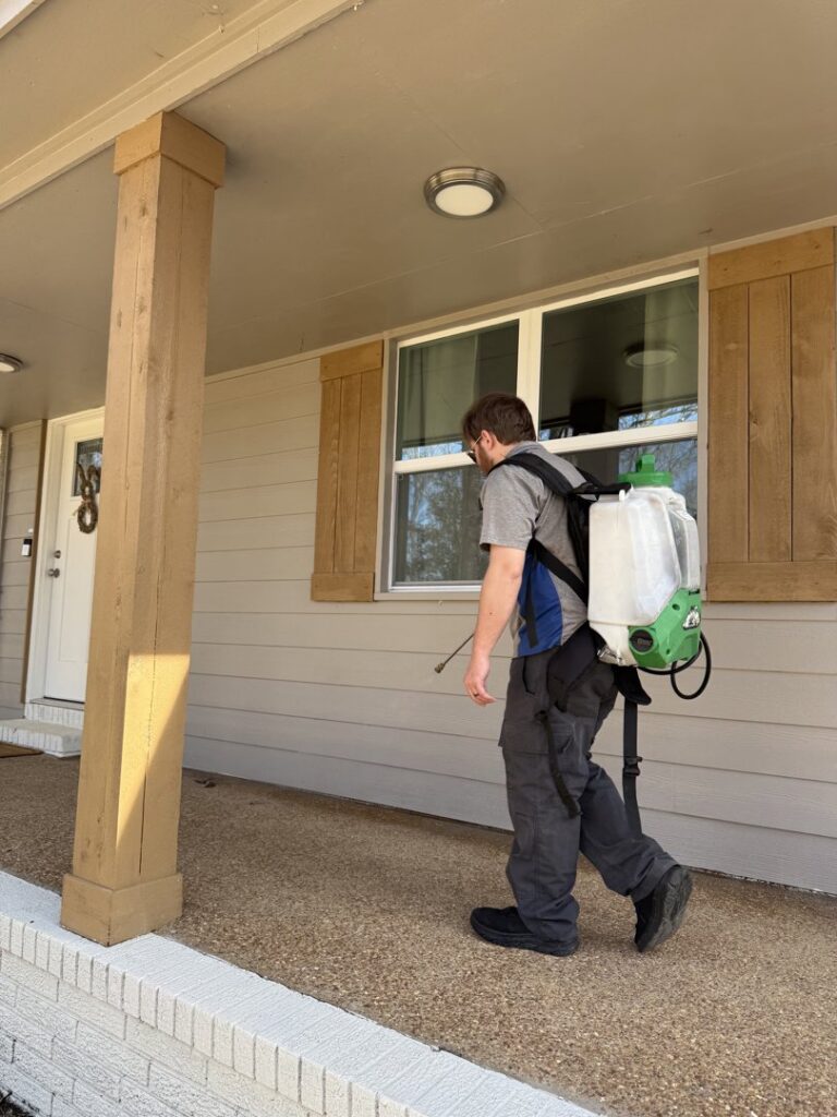 A Rosie's Pest Control technician with a backpack sprayer arriving at a residential home for service in Memphis, TN.