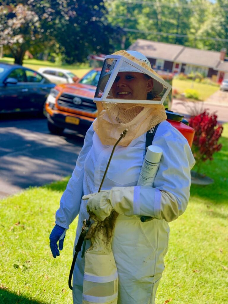 A Catseye Pest Control technician in a full bee suit with a sprayer, ready for a job in Hartford, CT.