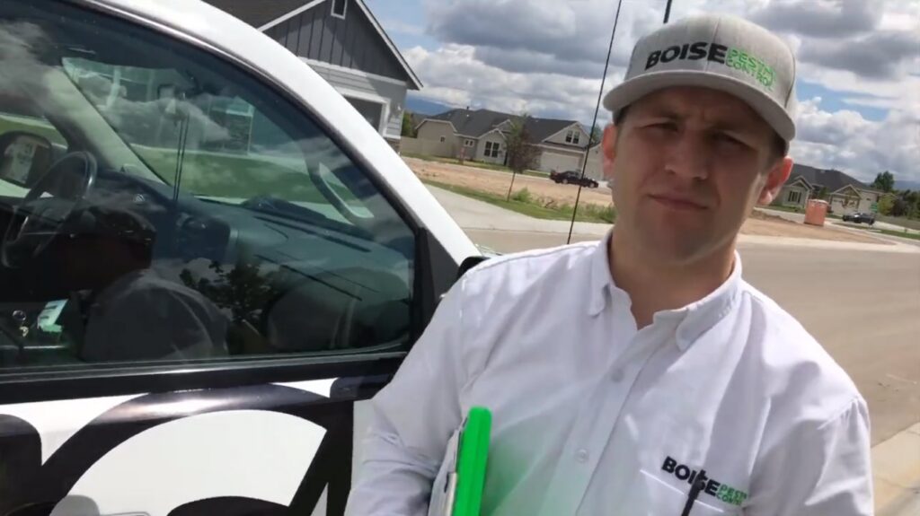 A Pest Control Service Boise technician with a clipboard next to a branded truck in Boise, ID, ready for a job.