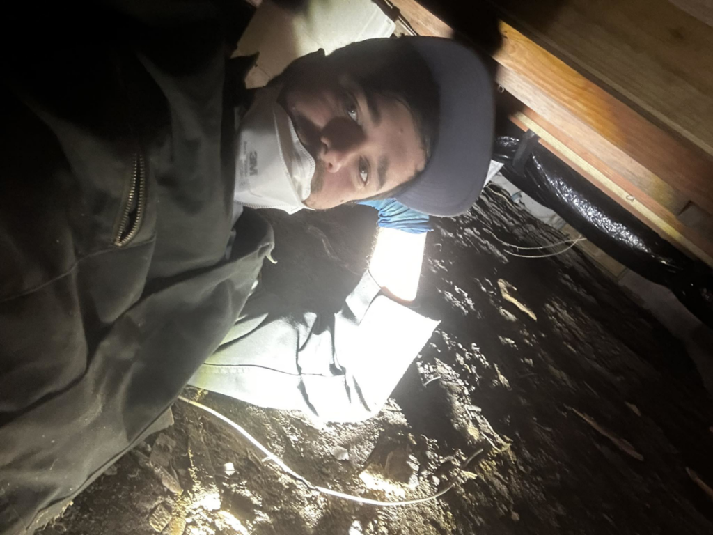 A pest control technician inspecting a crawl space for pests at Spartina Pest Management in Port Royal, SC.