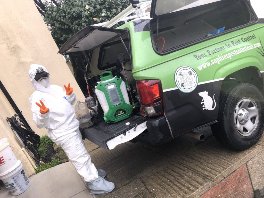 A pest control technician in a hazmat suit with equipment from Sophie's Pest Solutions in Oakland, CA, ready for a job.