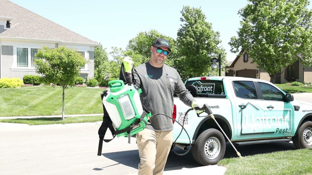 An Upfront Pest technician with a backpack sprayer and wand ready for service in North Kansas City, MO.